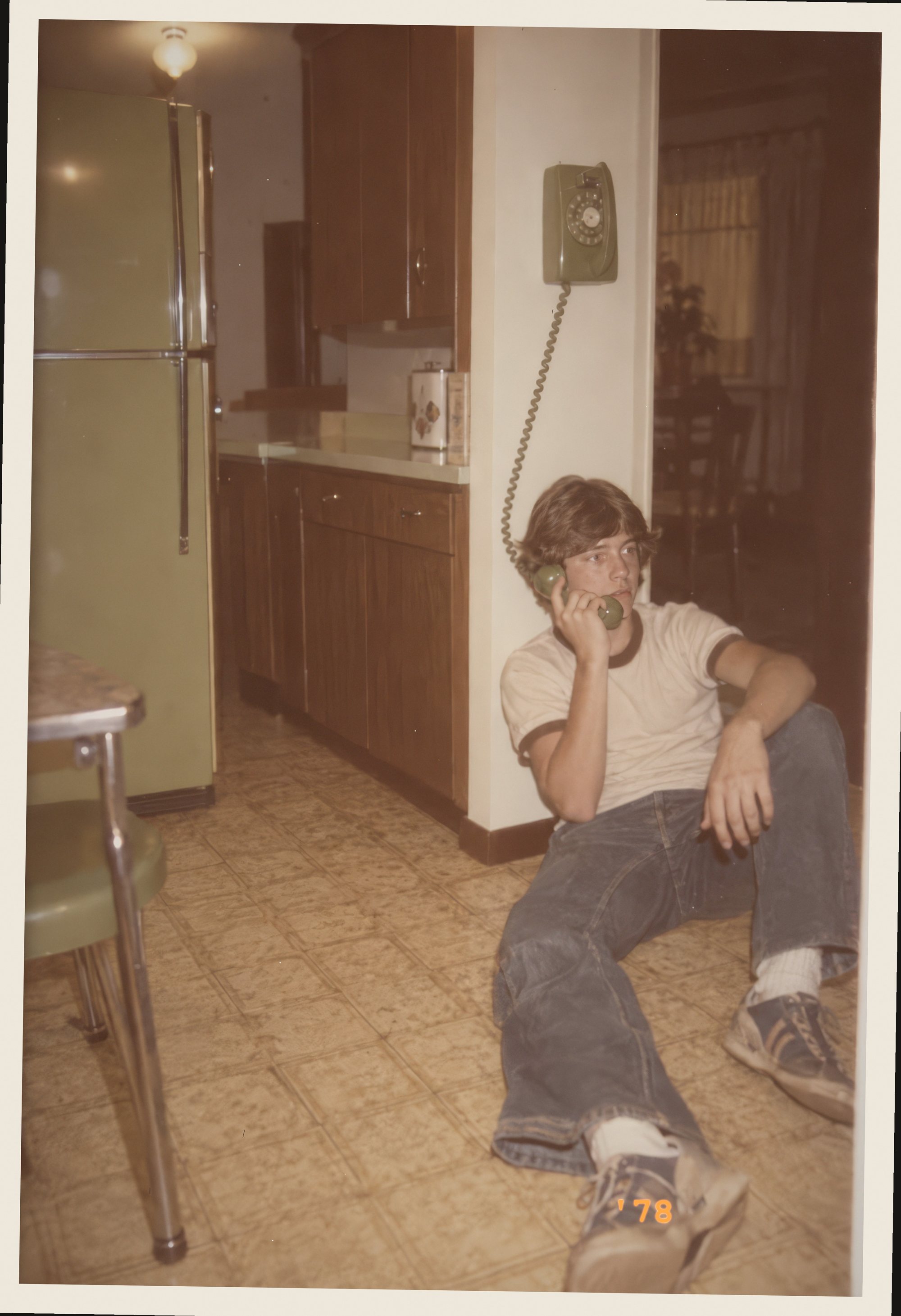 Teen on the kitchen floor with a rotary phone